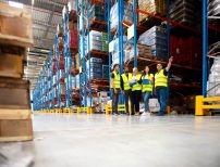 Shelving Shop Consultants showing plans to warehouse managers in a warehouse full of racking.