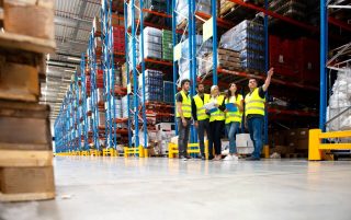 Shelving Shop Consultants showing plans to warehouse managers in a warehouse full of racking.