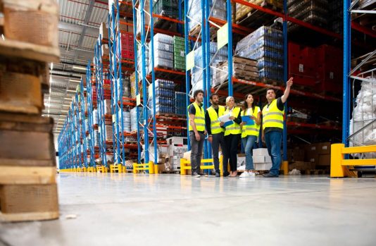 Shelving Shop Consultants showing plans to warehouse managers in a warehouse full of racking.